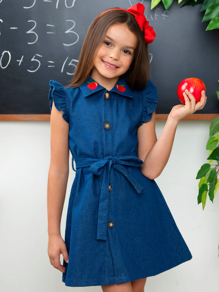Little girl wearing a blue denim flutter sleeve dress with embroidered apple collar and bow waist detail for back to school outfit