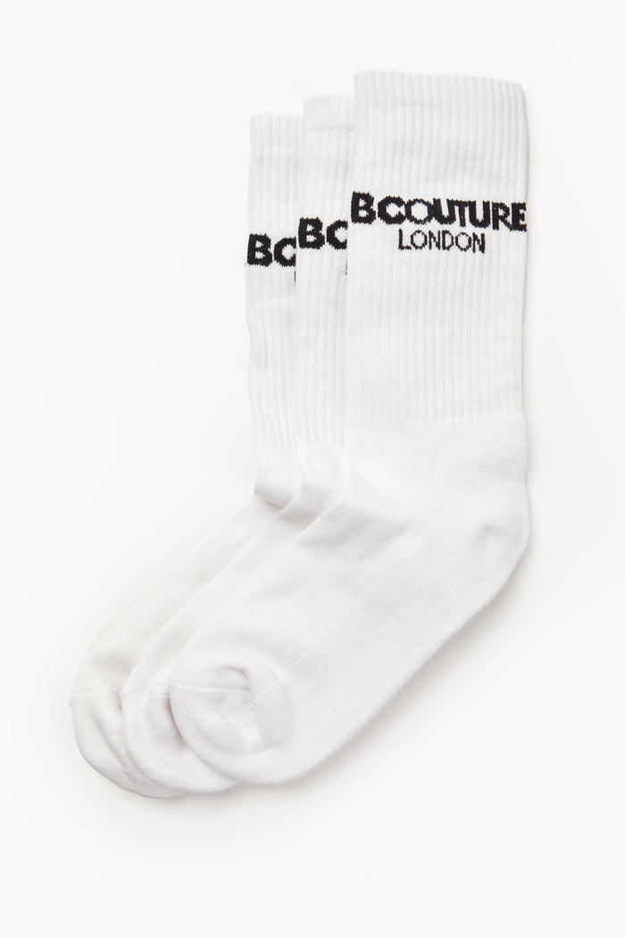 The Astell 3 Pack Socks in white feature bold “B COUTURE LONDON” text near the top. These white ribbed crew sports socks are made from breathable fabric and come displayed flat against a white background.