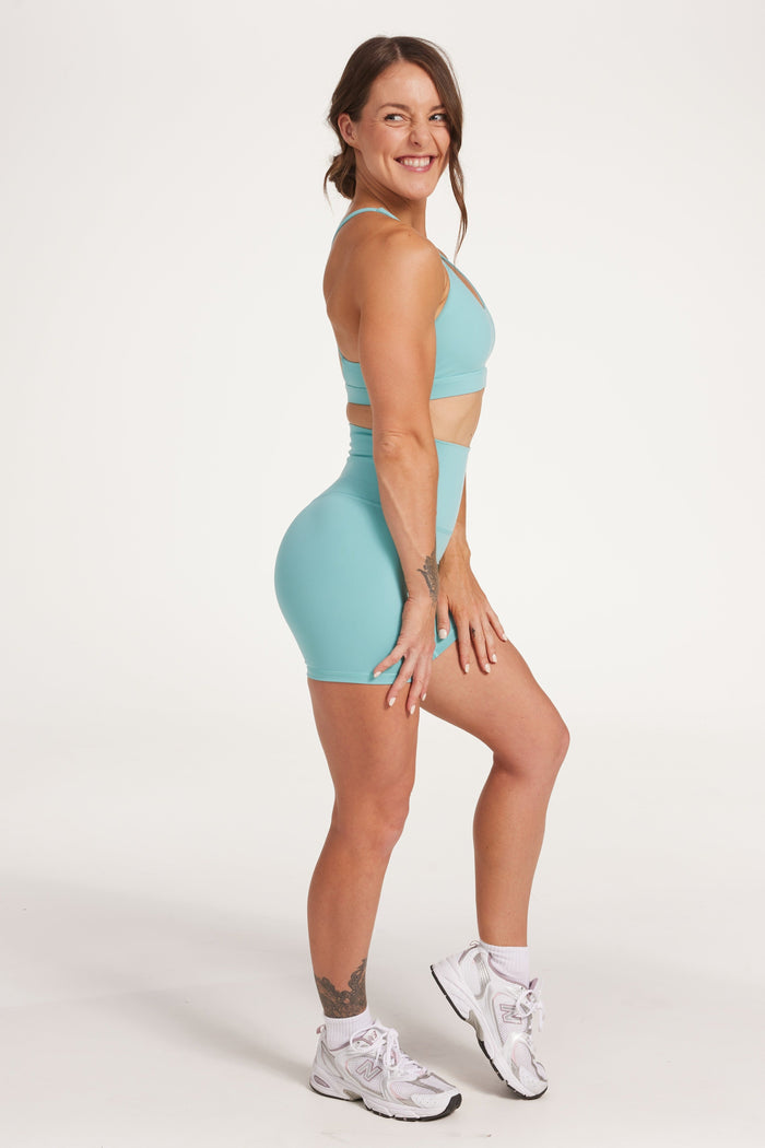 high waisted gym shorts, in buttery soft, supportive fabric with 6 inch inseam and no front rise seam, in lagoon green with women's moderate support activewear bra in buttery soft fabric with stunning triangle open back detail and scoop neckline