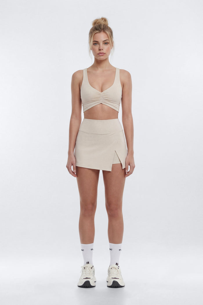 Woman wearing a beige sleeveless top and skirt set on a white background