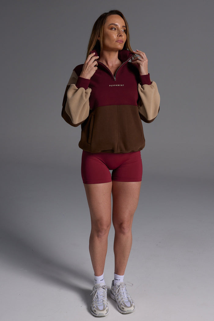 1/4 zip fleece jumper with double collar, ribbed stretchy fabric panel inserts, and two convenient zip pockets in a wine, chocolate and beige colour block design.