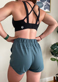 Running shorts in spruce green, with drawstring waistband, heat transfer logo in white and hem mesh panel feature
