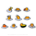 Gudetama Eggstra Lazy enamel pin from Kidrobot x Sanrio series, featuring a cute, blobby egg character on a white background.