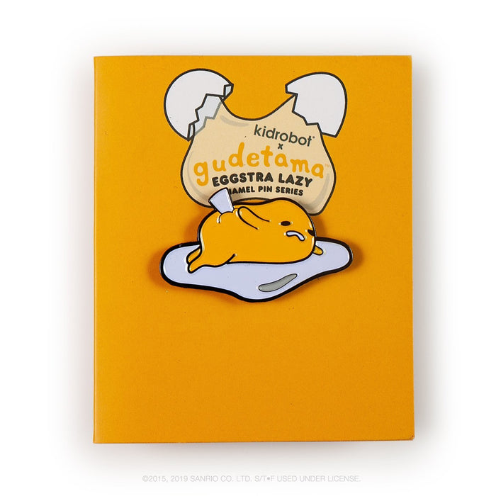 Sanrio Gudetama Eggstra Lazy enamel pin from Kidrobot series, featuring a cute, relaxed egg character on a boxed pin display.