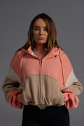 Full zip coral and desert fleece hoodie styled with black leggings, showing cropped length and structured silhouette