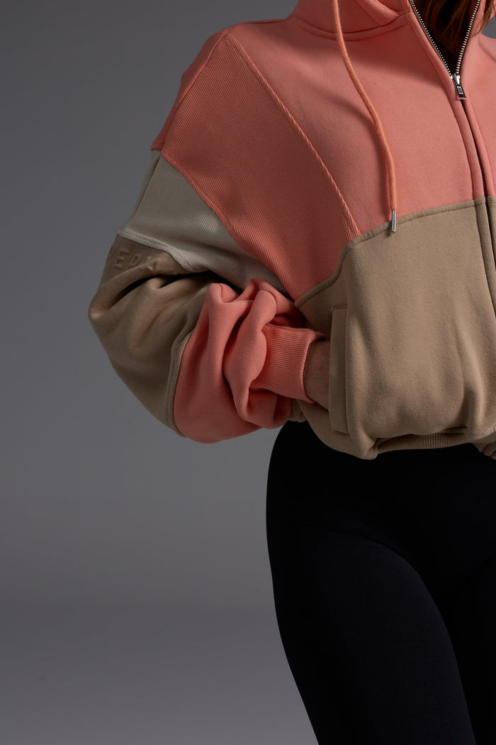 Side view showing the deliberately cropped length of the coral and desert fleece hoodie, perfect for high-waisted activewear