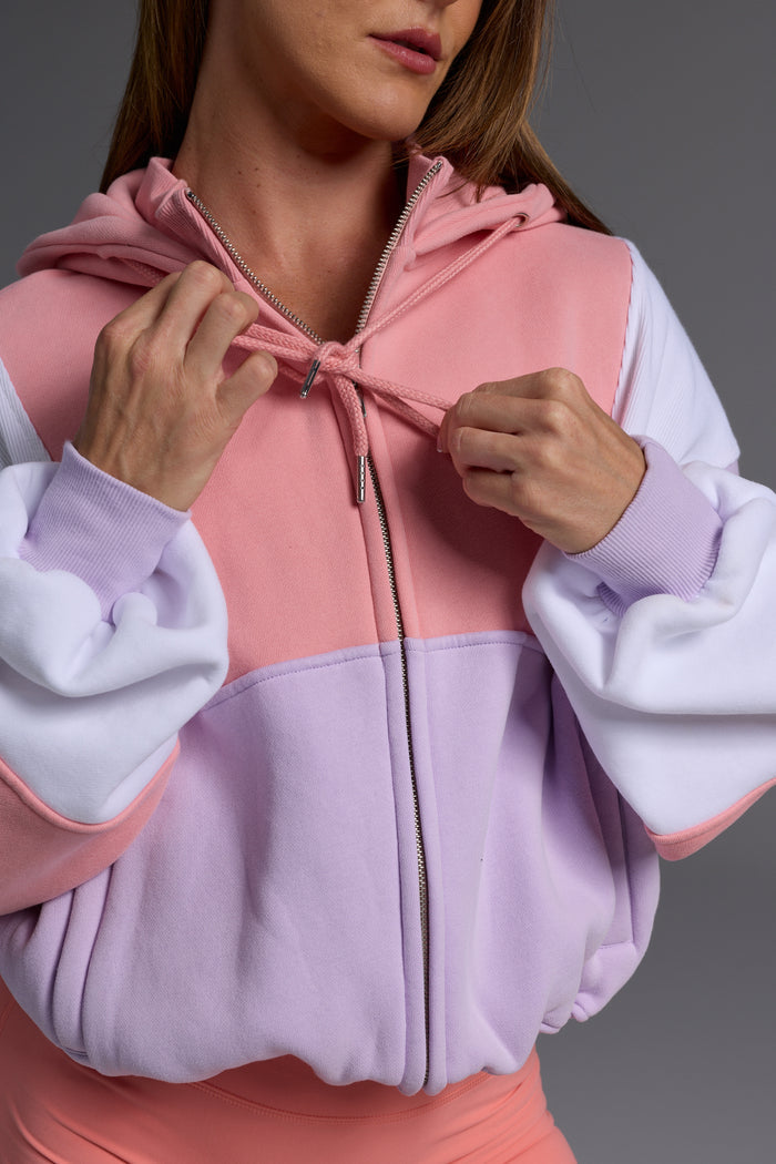 Close-up detail of peach, lilac and white colour-blocked fleece hoodie showing oversized fit and hood detail
