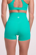 Buttery soft high waisted women's gym shorts with 4" inseam with curved stitched detailing for a butt shaping effect, and no front rise seam, paired with a high neck women's sports bra with a supportive elasticated hem and triple layered fabric with removable pads for extra support and crossover back straps in cyan green