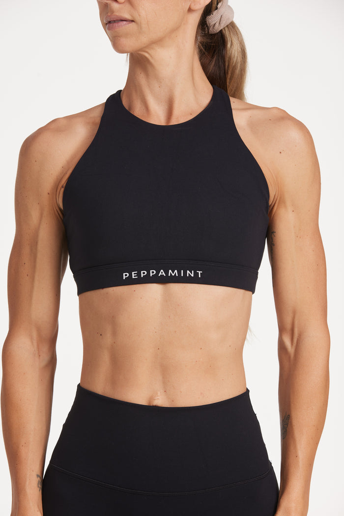 Buttery soft high waisted women's gym shorts with 4" inseam with curved stitched detailing for a butt shaping effect, and no front rise seam, paired with a high neck women's sports bra with a supportive elasticated hem and triple layered fabric with removable pads for extra support and crossover back straps in Black.