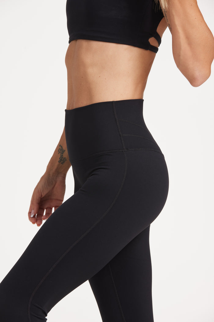 Buttery soft high waisted women's gym tights with curved hem stitched detailing for a butt shaping effect, and no front rise seam, paired with an open back women's crop t-shirt with a supportive elasticated hem and triple layered fabric with removable pads for extra support and aesthetic cross back straps in Black.