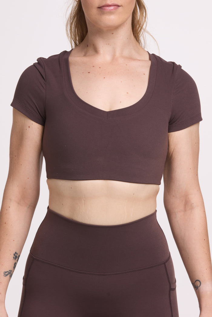 Buttery soft high waisted women's gym tights with practical pockets, sweetheart back seams for an upper glute shaping effect, and no front rise seam, paired with an V neck women's crop t-shirt with a supportive elasticated hem and triple layered fabric with removable pads for extra support in chocolate