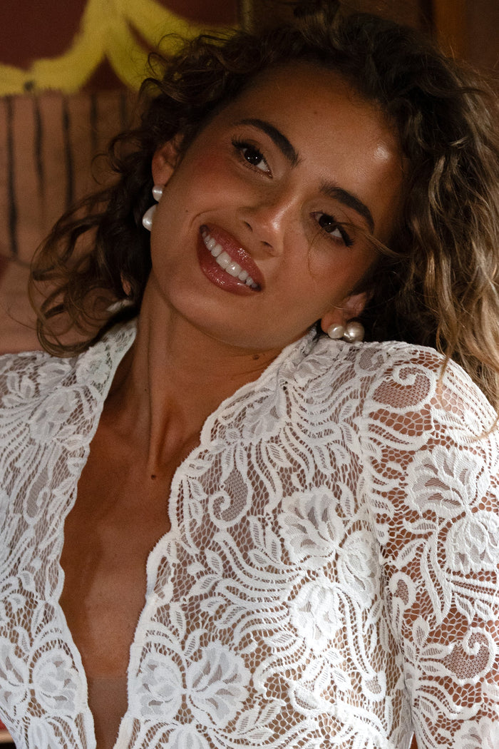 Woman wearing a white lace wedding gown and pearl earrings