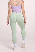 Front cross over strap activewear bra in seamless fabric with adjustable back straps, and ribbed supportive under bust band with seamless gym tights with booty contouring panels, invisible scrunch technology, sweetheart shaped back seams and thick supportive fabric in mist green