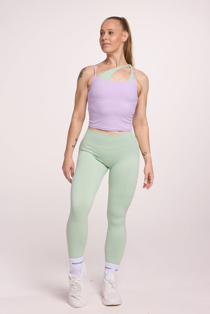 Buttery soft singlet with ruched side seams, spaghetti straps and built in shelf bra with removable pads in lavender with seamless gym tights with booty contouring panels, invisible scrunch technology, sweetheart shaped back seams and thick supportive fabric in mist green